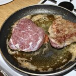 dwa policzki wołowe smażą się na patelni