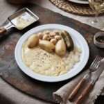 raclette z ziemniakami gotowanymi i kiszonkami podany na talerzu