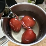 w garnku trzy duże pomidory zalewane są gorącą wodą