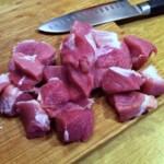 wieprzowina pokrojona w grubą kostkę na desce kuchennej