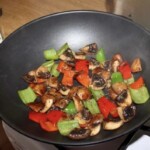 na patelni smażą się drobno pokrojone kolorowe papryki i pieczarki