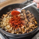 krojone świeże grzyby leśne smażą się na patelni razem z mieloną słodką papryką