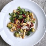Gotowana brukselka smażona z plastrami chorizo i grzybami shimeji na koniec posypana parmezanem.