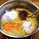 w garnku znajdują się starte ziemniaki oraz wbite jajko, mąka, sól i zmielony pieprz na placki ziemniaczane