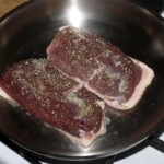 na patelni smażą się dwa piersi z kaczki