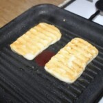 na patelni grillowej smażą się dwa plastry sera halloumi