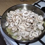 na patelni smażą się pokrojone w plasterki pieczarki