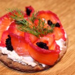 gravlax z burakiem i chrzanem pokrojony w plastry i położony na kromce chrupkiego chleba