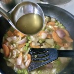 na patelni smażą się pokrojone w kostkę warzywa, które są podlewane wywarem jarzynowym