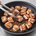 na patelni smaży się mięso wieprzowe pokrojone w kostkę na gulasz