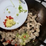 w woku smażą się małe kawałki mięsa z kurczaka