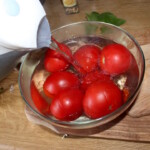 w szklanej misce dojrzałe pomidory są parzone wrząca wodą