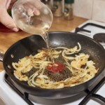 na patelni smaży się pokrojona w piórka cebula, która jest podlewana białym winem