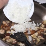 na patelni smażą się pokrojone pieczarki i drobno siekana cebula