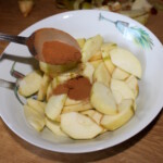 w dużej misce znajdują się cząstki jabłka posypane cynamonem