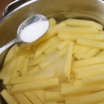 pokrojone na frytki ziemniaki w garnku z wodą