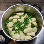 w garnku znajdują się pokrojone ziemniaki i groszek