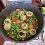 w głębokiej patelni smaży się groszek oraz serca karczochów i marchewka w plasterkach