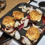 na patelni grillowej smażą się udka z kurczaka oraz kawałki czerwonej cebuli