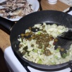 na patelni smażą się kapary, siekany fenkuł i smażone sardynki w kawałkach