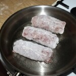trzy duże rolady śląski obtoczone w mące smażą się na patelni