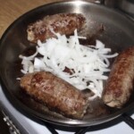 trzy duże rolady śląskie smażą się na patelni razem z posiekaną cebulą