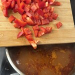 drobno krojona czerwona papryka wrzucana jest do zupy chilli