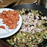 na dużej patelni smażą się drobno posiekana cebula oraz kiełbasa