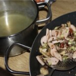 na dużej patelni smażą się drobno posiekana cebula oraz kiełbasa