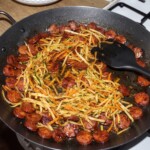 na patelni smażą się starte warzywa oraz kiełbasa krojona
