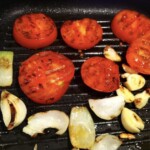 na patelni grıllowej smażą się plastry pomidora i kawałki cebuli