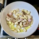 na patelni smażą się ząbki czosnku i siekana cebula