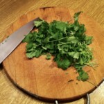 siekana świeża kolendra na drewnianej desce kuchennej