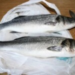 dwa świeże labraksy na stole w kuchni