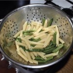 na durszlaku znajdują się odcedzony ugotowany makaron oraz zielona fasolka szparagowa