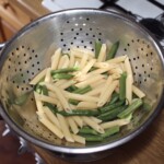 w durszlaku znajduje się ugotowany makaron penne i zielona fasolka szparagowa