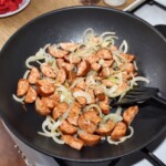 na dużej patelni smaż się krojona w talarki kiełbasa oraz cebula krojona w piórka