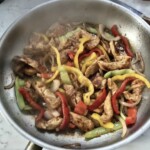 na patelni smażą się paski piersi z kurczaka i paski kolorowych papryk