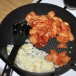 na patelni smaży się pokrojony w kawałki filet z kurczaka razem z cebulką