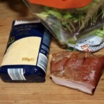 paczka polenty, kawałek boczku surowego wędzonego i świeża bazylia w doniczce