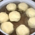 Knedle ze śliwkami górują się w dużym garnku w wodzie