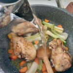 kawałki kurczaka smażą się na patelni z krojonymi warzywami