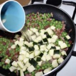 na patelni smaży się pokrojona drobni szynka szwarcwaldzka, groszek i cukinia