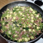 na patelni smaży się pokrojona drobni szynka szwarcwaldzka, groszek i cukinia