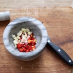 w moździerzu znajduje się papryczka chilli i czosnek siekany