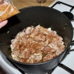 w garnku smaży się drobno siekana cebula i kawałki mięsa z kurczaka