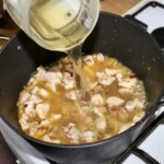 w garnku smaży się drobno siekana cebula i kawałki mięsa z kurczaka