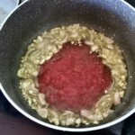 w głębokim garnku smaży się drobno siekana cebula i starte pomidory na oliwie