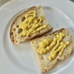 dwie kromki chleba posmarowane musztardą