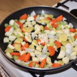 na dużej patelni smażą się pokrojone warzywa